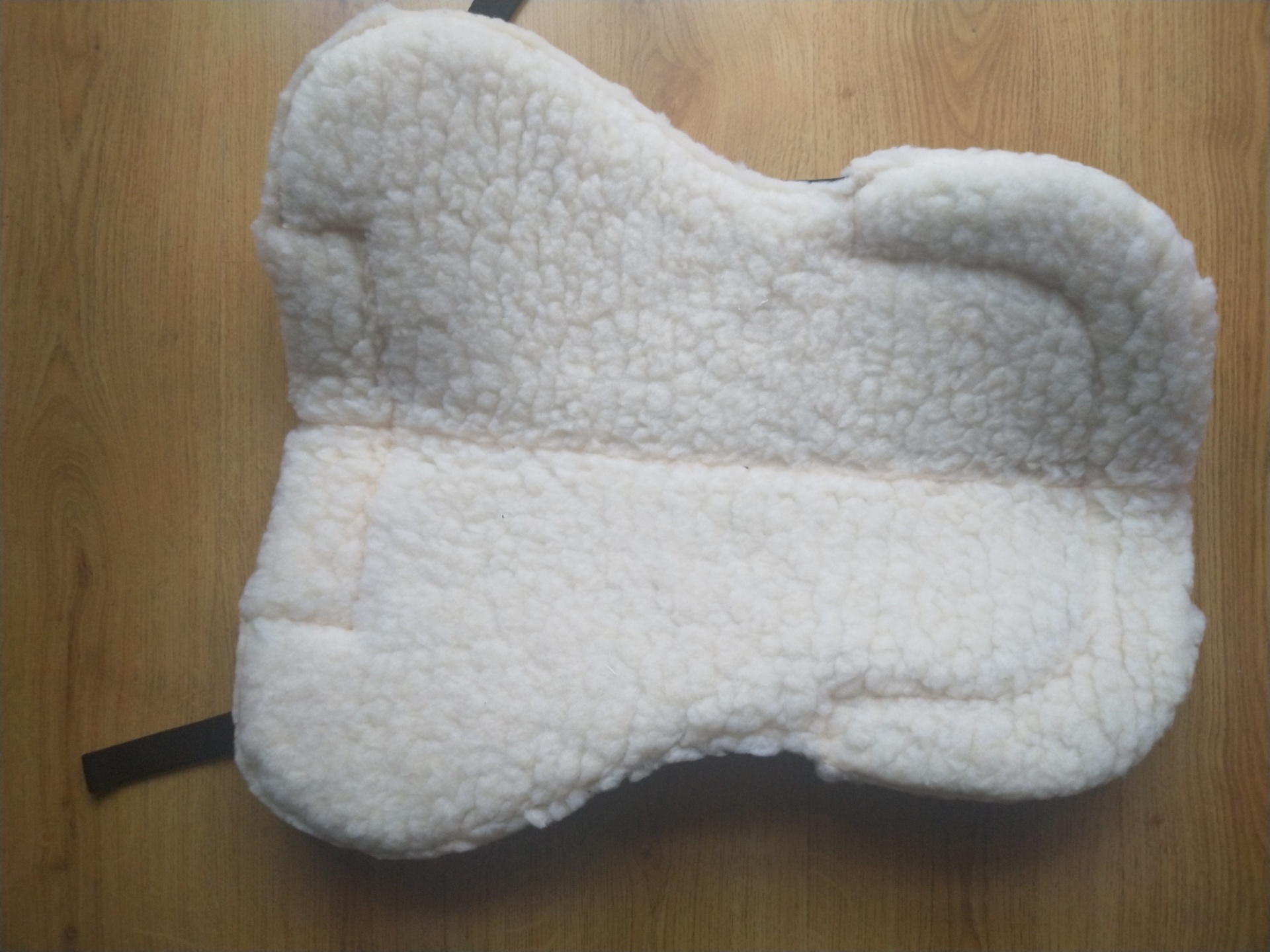 Almofada branca de tecido peludo sobre chão de madeira