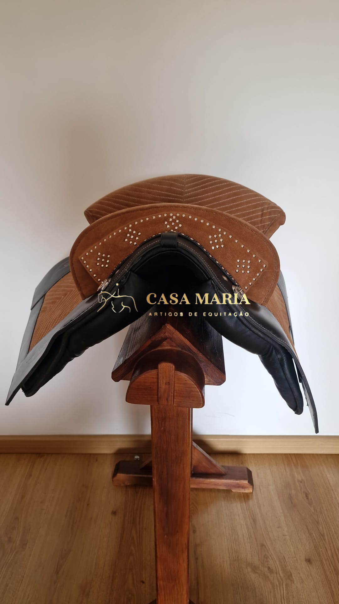 Sela de equitação castanha e preta em suporte de madeira