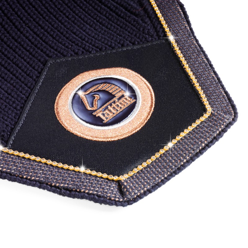 Detalhe de tecido azul escuro com emblema dourado e azul Hermes e fita dourada