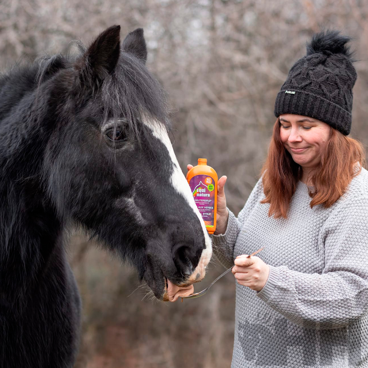 Mulher a alimentar cavalo com colher e frasco laranja ao ar livre