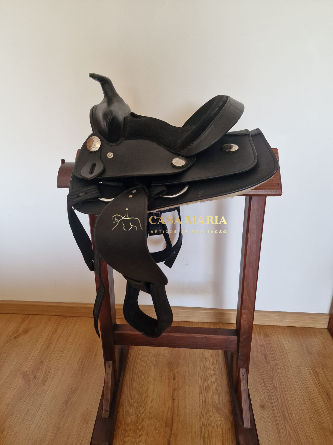 Sela preta de equitação em couro sobre suporte de madeira