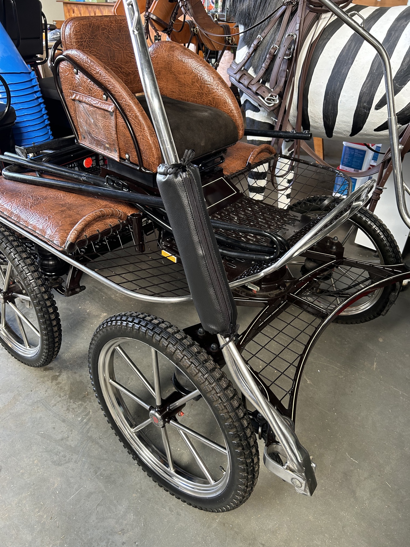 Carrinho de duas rodas com estofos castanhos e estrutura metálica preta