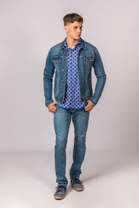 Homem com casaco de ganga, camisa azul com padrão e jeans azul