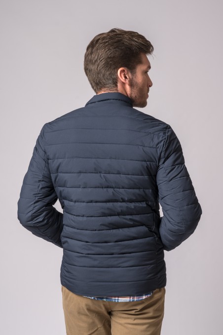 Homem de costas a usar casaco acolchoado azul escuro com riscas horizontais