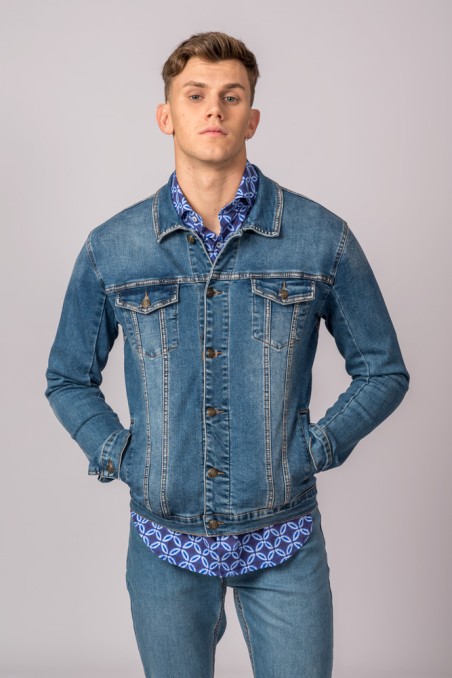 Homem com casaco de ganga azul, camisa azul estampada e jeans azuis
