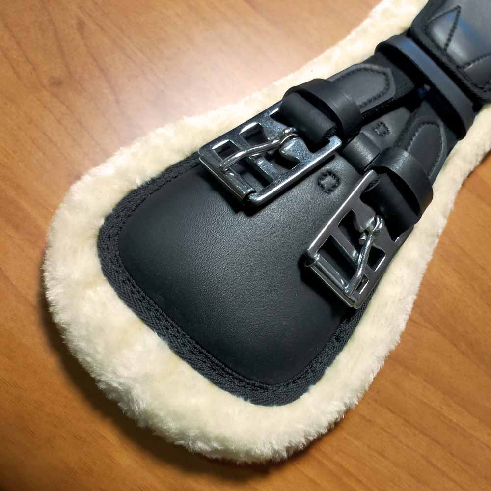 Protector de couro preto com interior de pelo branco e duas fivelas metálicas prateadas