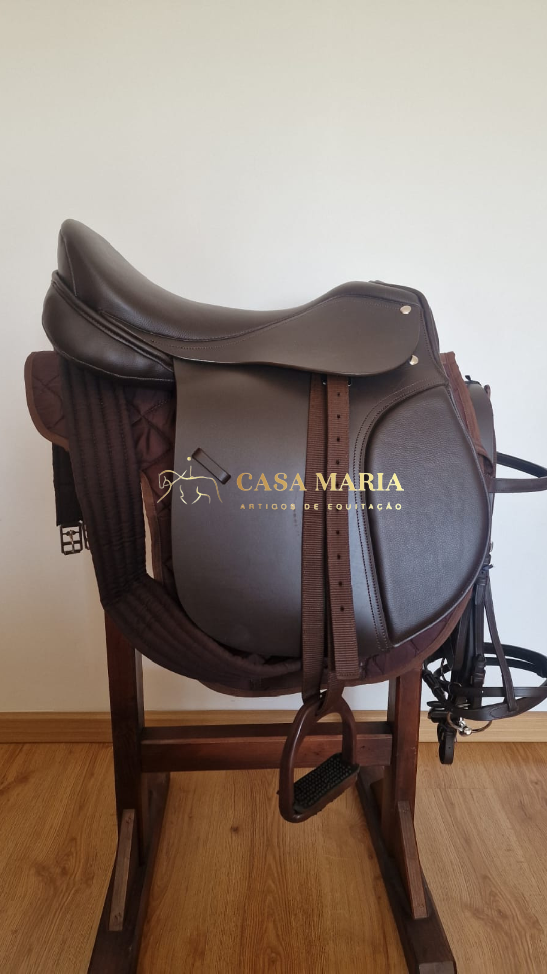Sela de equitação castanha em couro com estribo e correias num suporte de madeira