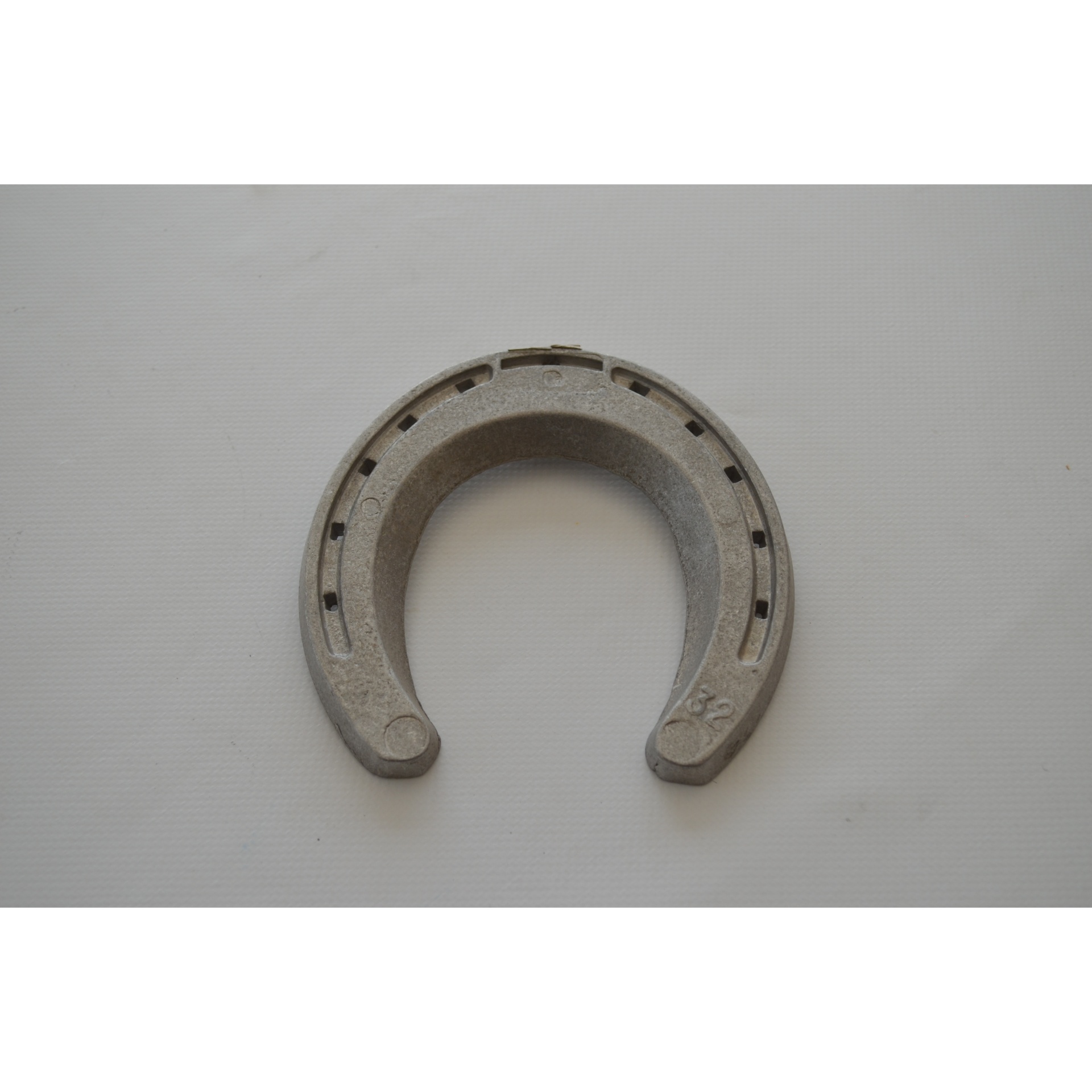 ferradura metálica cinzenta sobre fundo branco