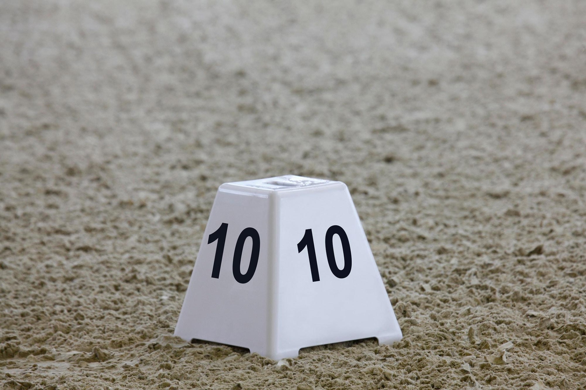 Cone branco com o número 10 em preto sobre areia