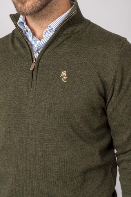 Camisola verde de malha com fecho de correr e estampagem BC, usada com camisa azul clara por baixo