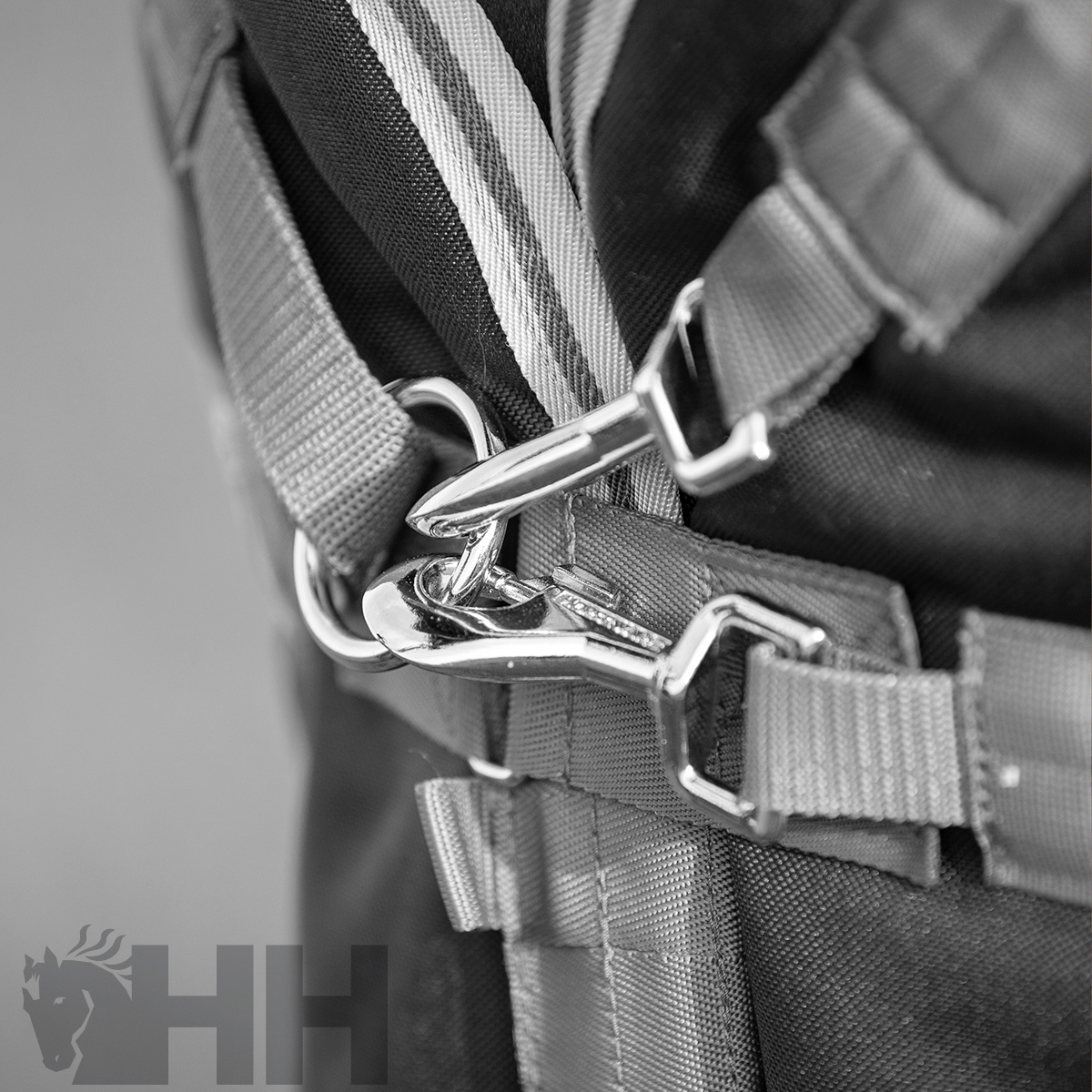Mochila preta com alças e clips metálicos fechados, com logótipo 'HH' visível.