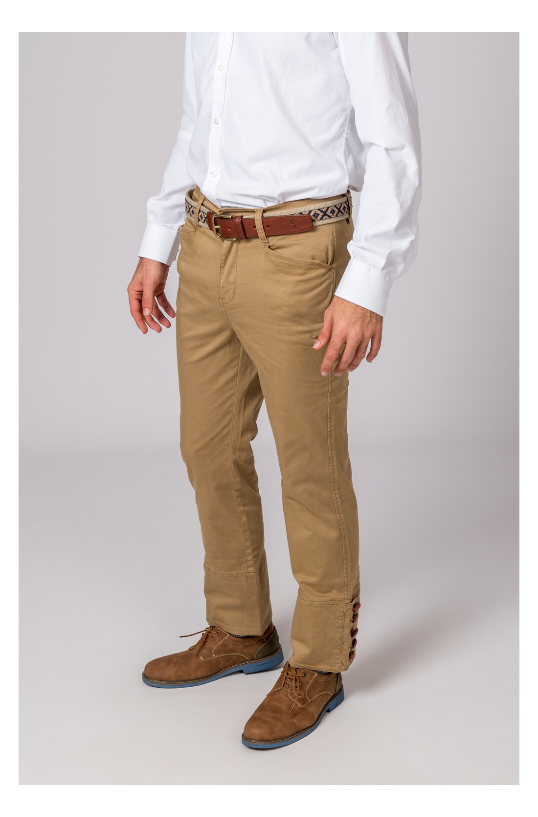 Calças bege, camisa branca, cinto castanho padrão e sapatos camurça castanhos.
