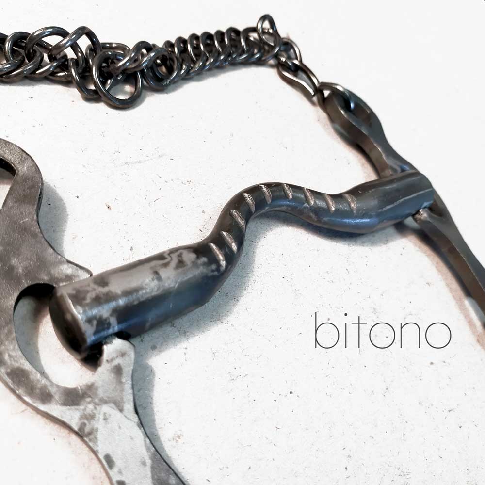 Produto metálico envelhecido com corrente e peça curva sobre fundo branco com palavra bitono
