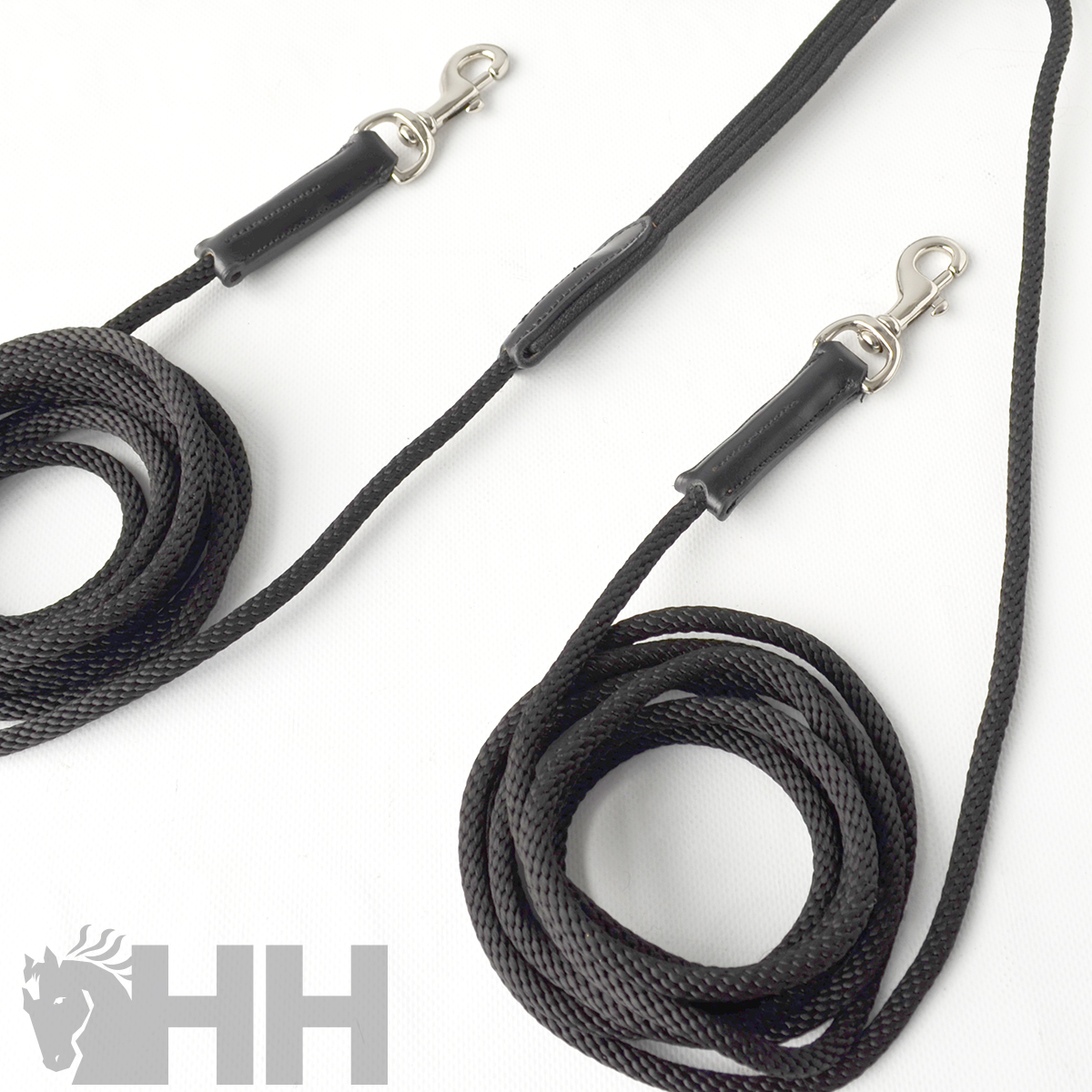 Duas trelas pretas para cão com ferragens metálicas e couro, sobre fundo branco com logótipo HH.