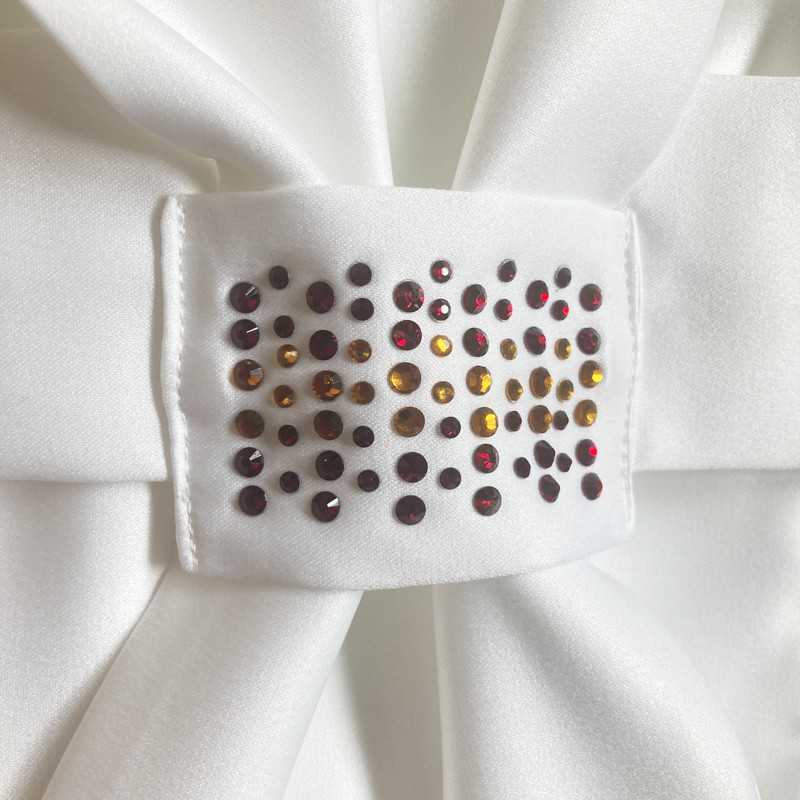 Detalhe de adorno com pedras brilhantes em pano branco