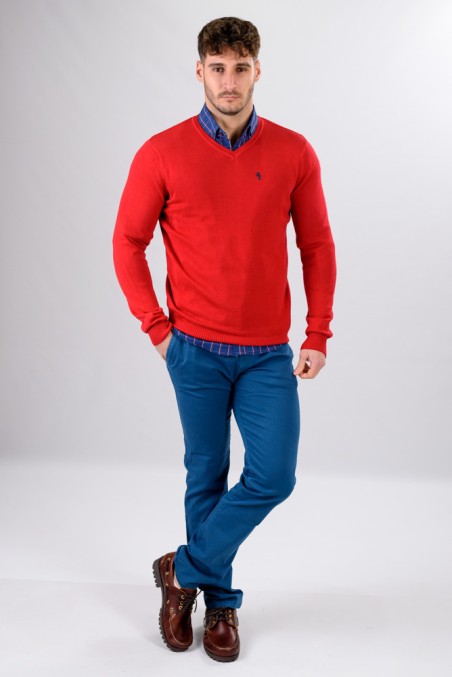 Homem com camisola vermelha e calças azuis numa pose frontal em fundo branco