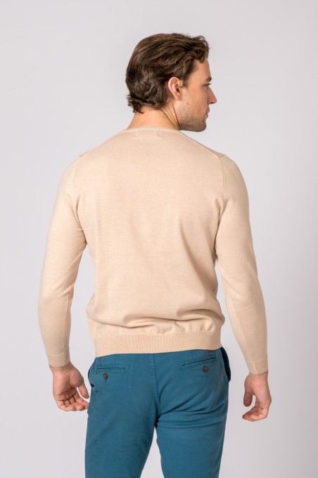 Homem de costas com camisola bege e calças azuis