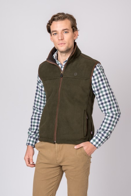 Homem com colete verde-escuro, camisa xadrez e calças bege