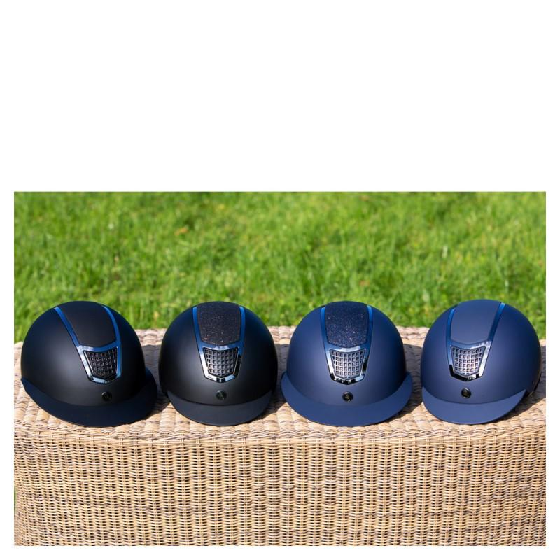 Quatro capacetes de equitação azul escuro e preto com detalhes prateados sobre superfície de vime