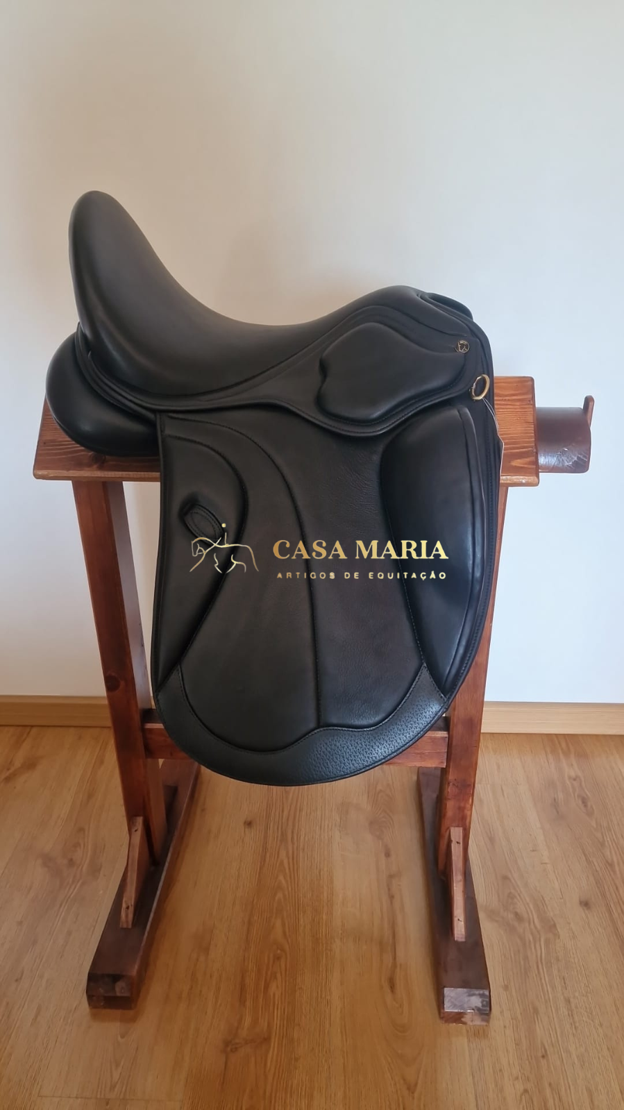 Sela de equitação preta em couro sobre cavalete de madeira