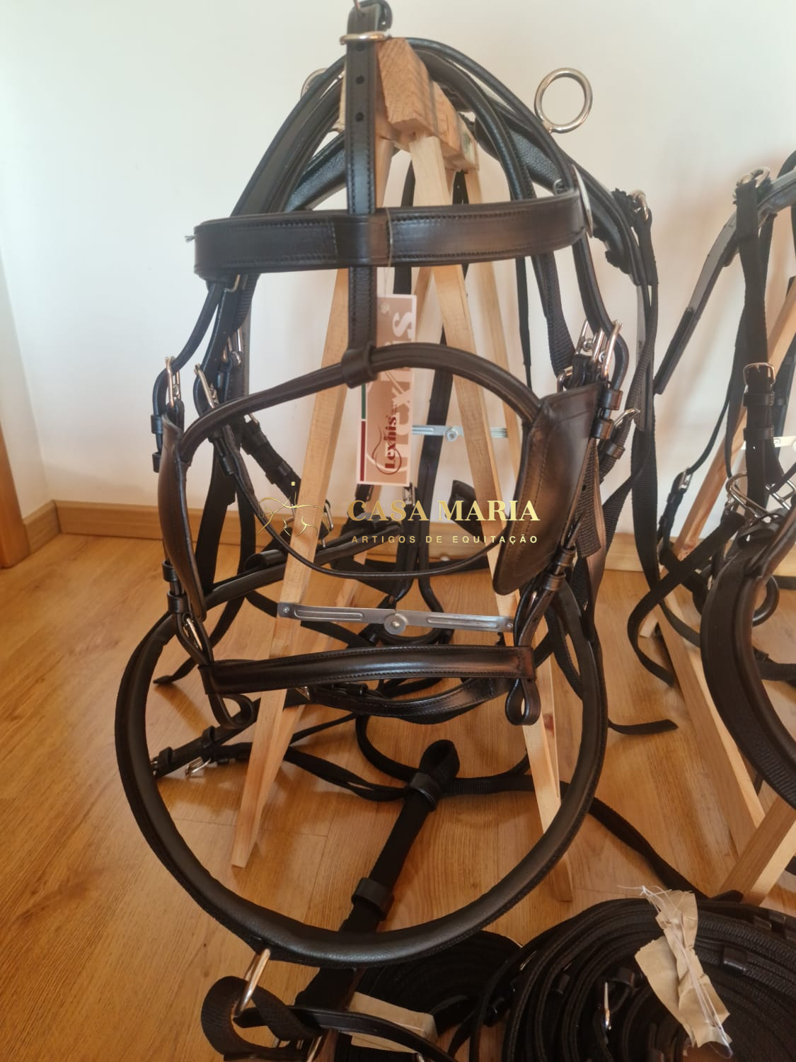 Lançadeira de couro preto com ferragens metálicas apoiada em estrutura de madeira