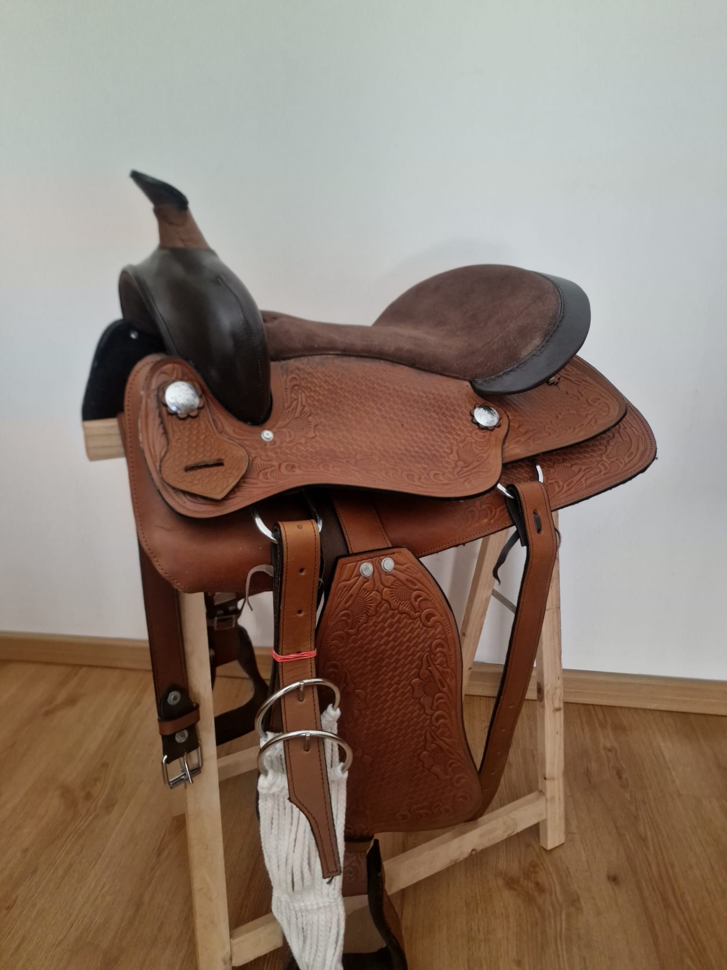 Sela de montaria em pele castanha com texturas e detalhes em madeira escura