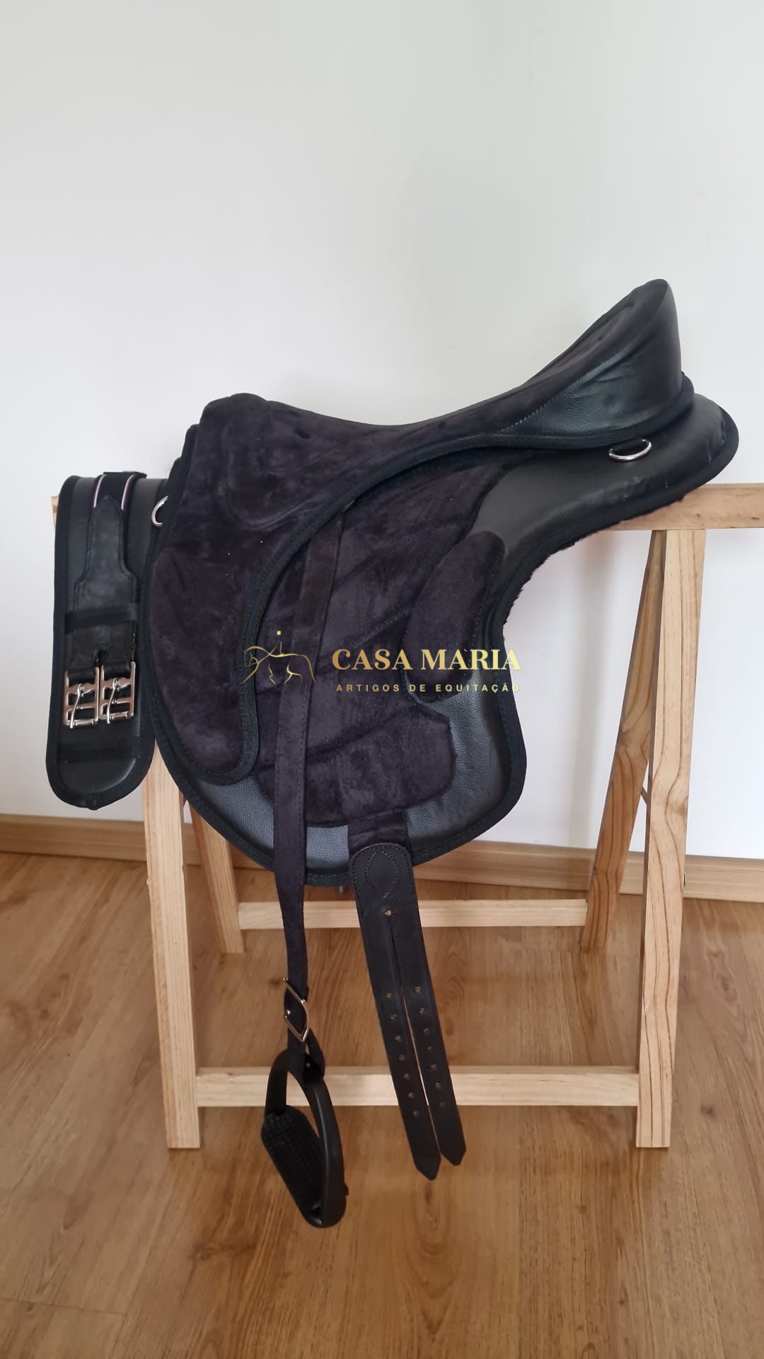 Sela de equitação preta em couro e tecido aveludado sobre estrutura de madeira