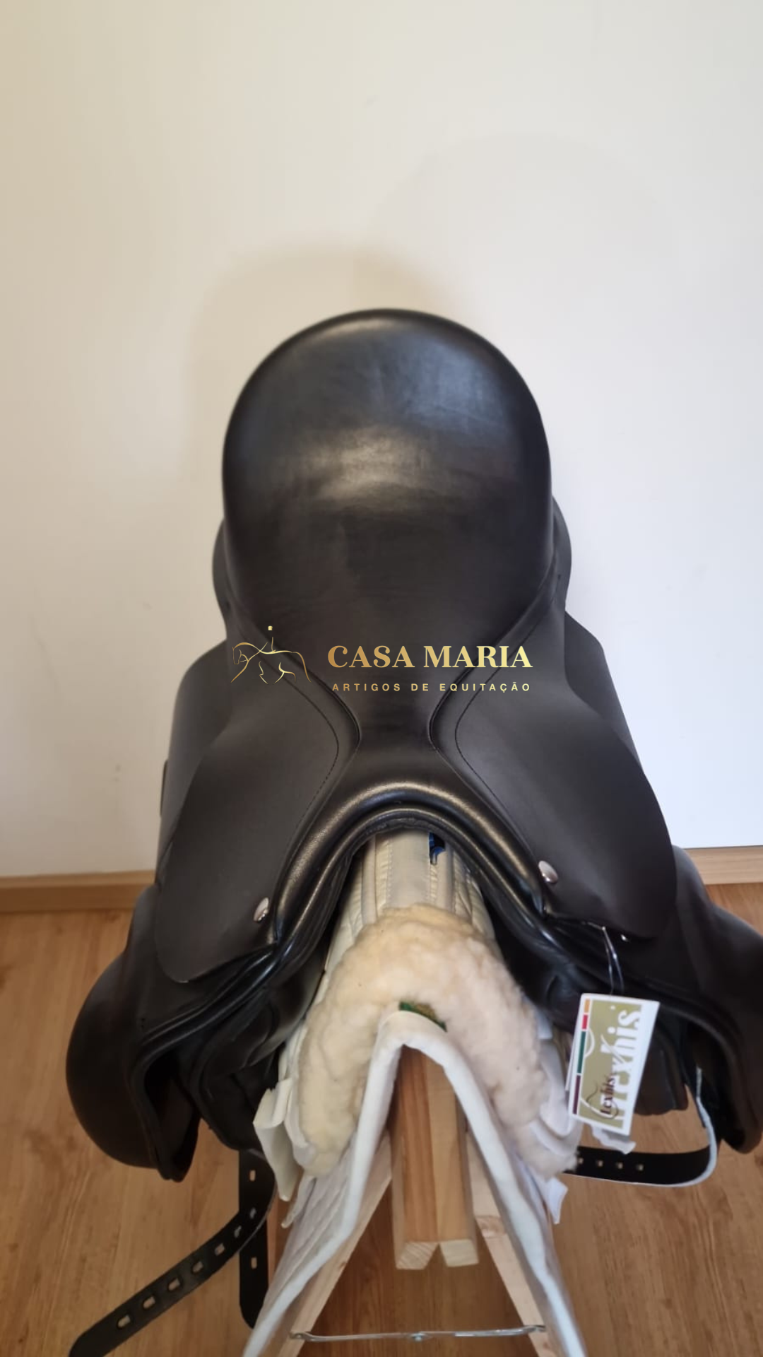 Sela de equitação preta em couro sobre suporte de madeira com forro acolchoado branca
