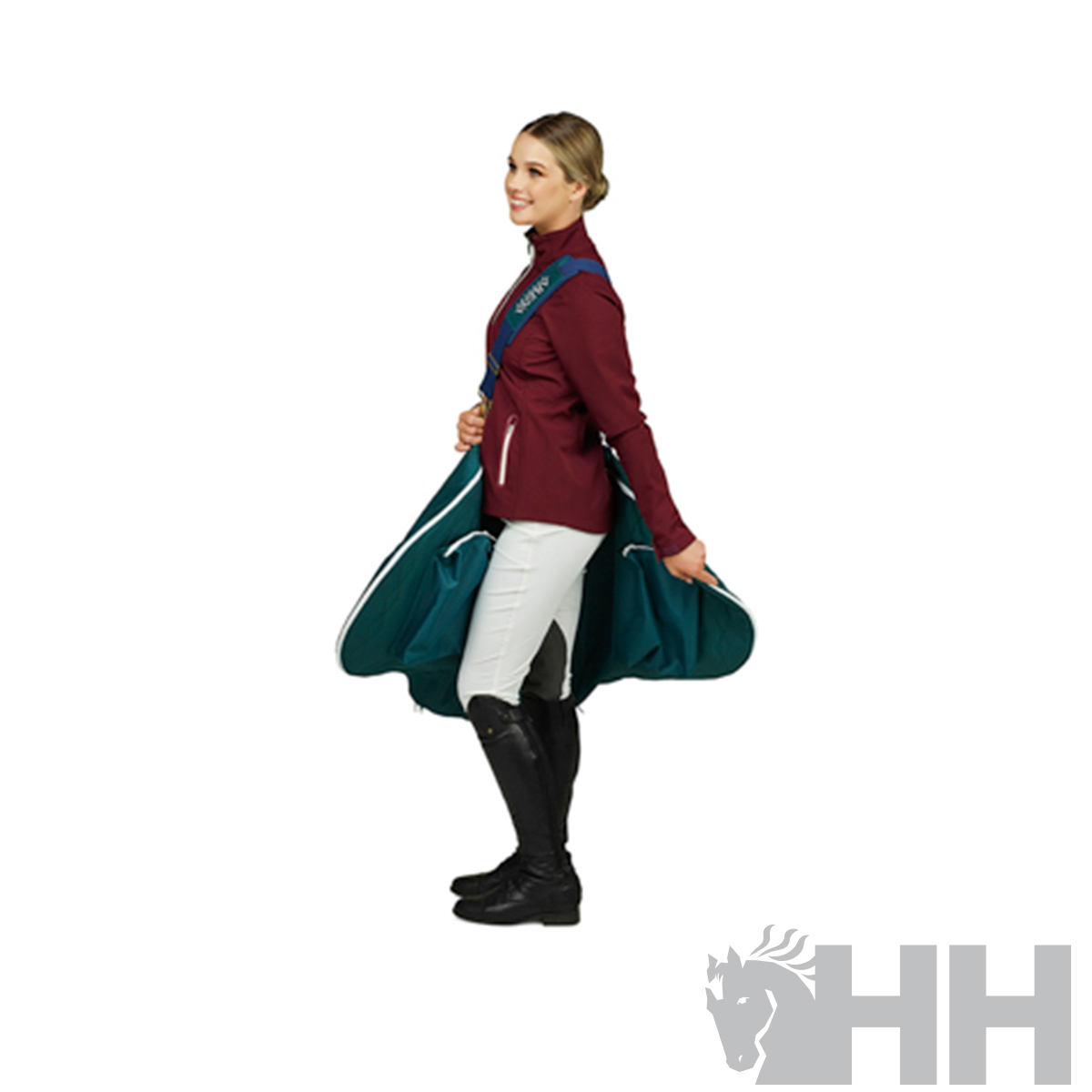 Mulher com casaco borgonha, calças brancas e botas pretas segurando cobertor verde escuro