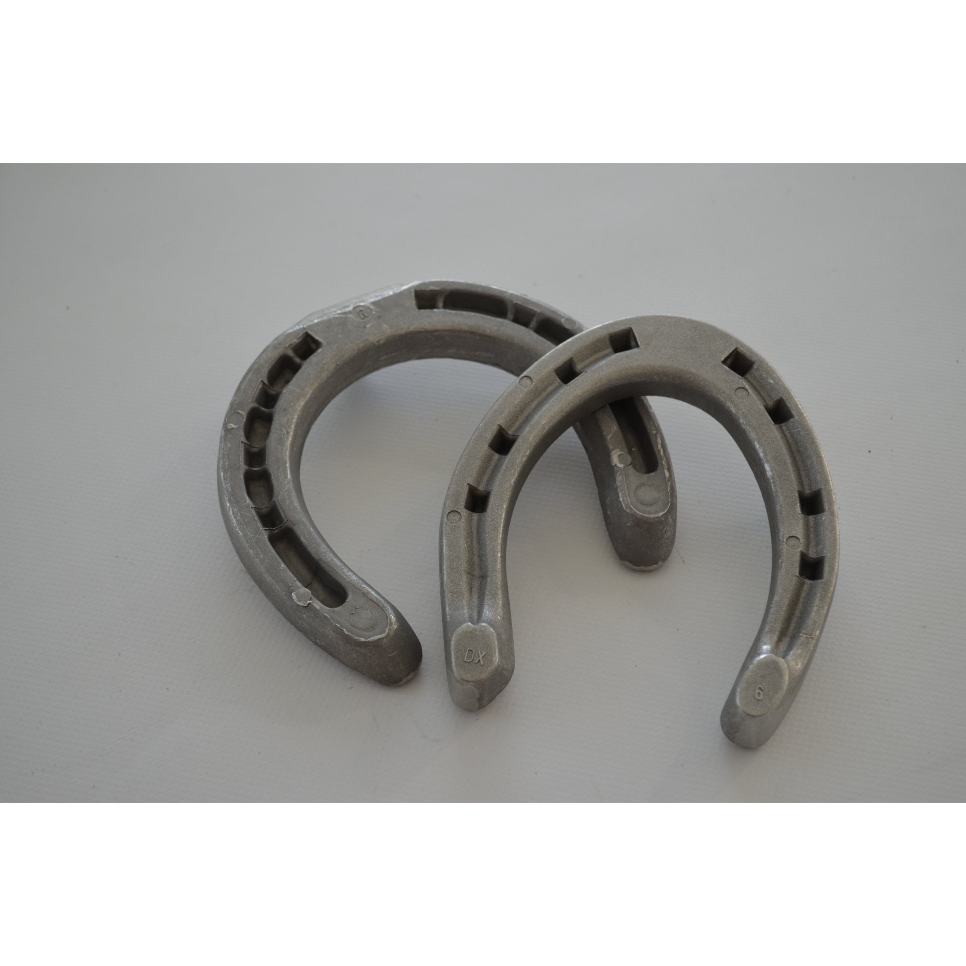 Duas ferraduras metálicas prateadas sobre superfície branca