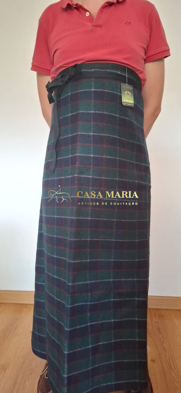 Saia xadrez comprida com laço preto na cintura, usada com camisola polo vermelha