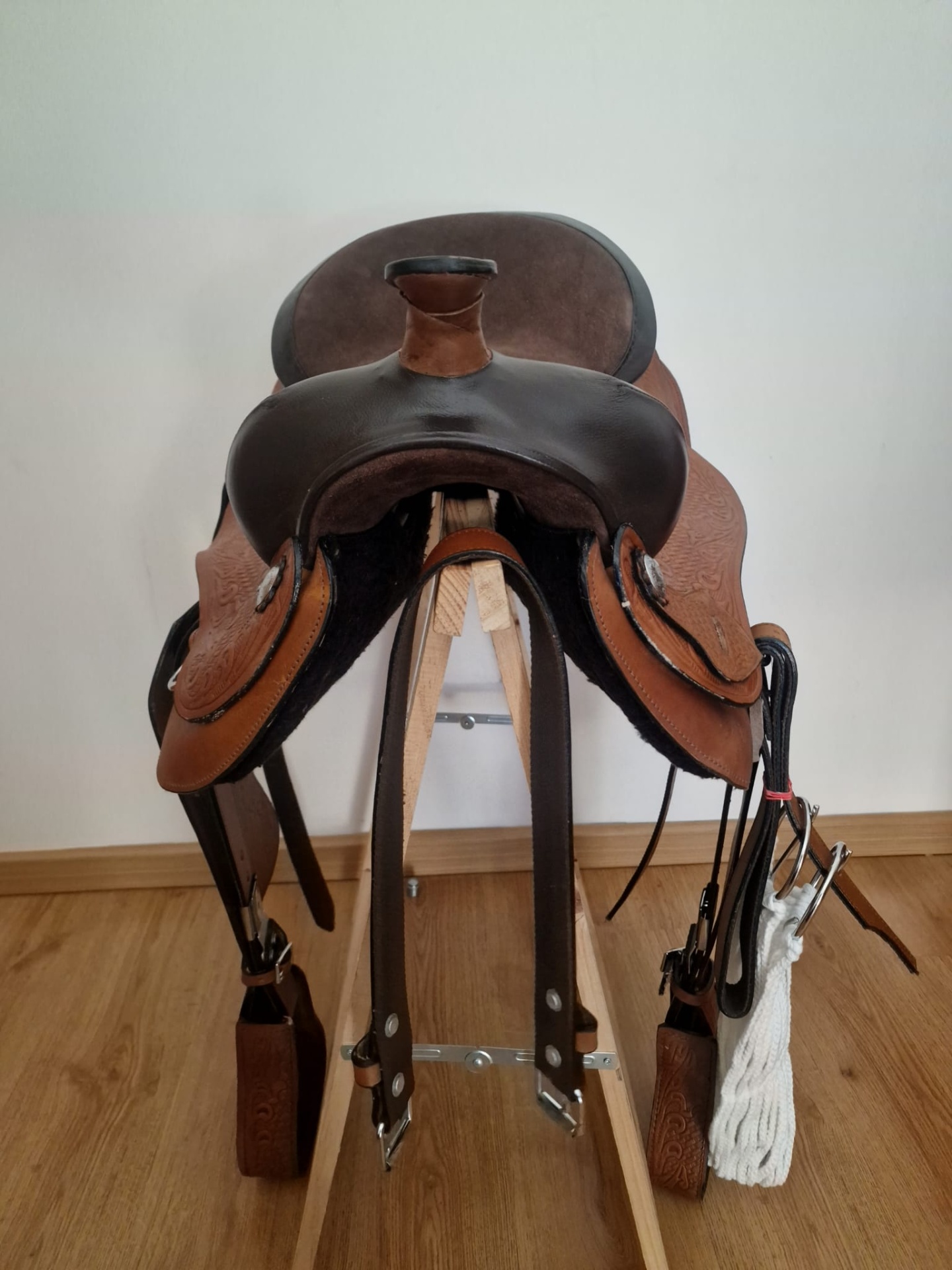 sela de equitação castanha em suporte de madeira