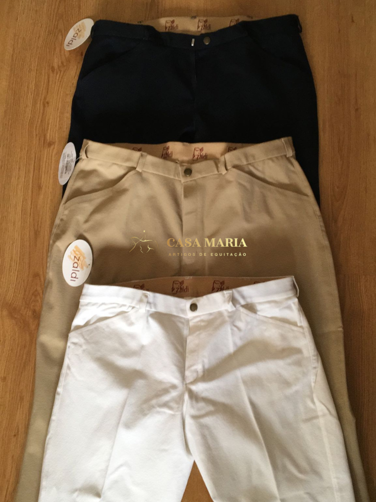 Três calças de equitação azul escuro, bege e branco sobre fundo de madeira clara