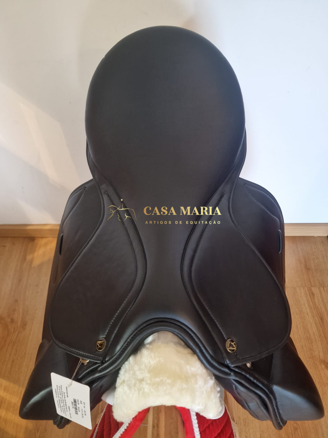 Sela de equitação castanha escura com interior felpudo branco sobre suporte