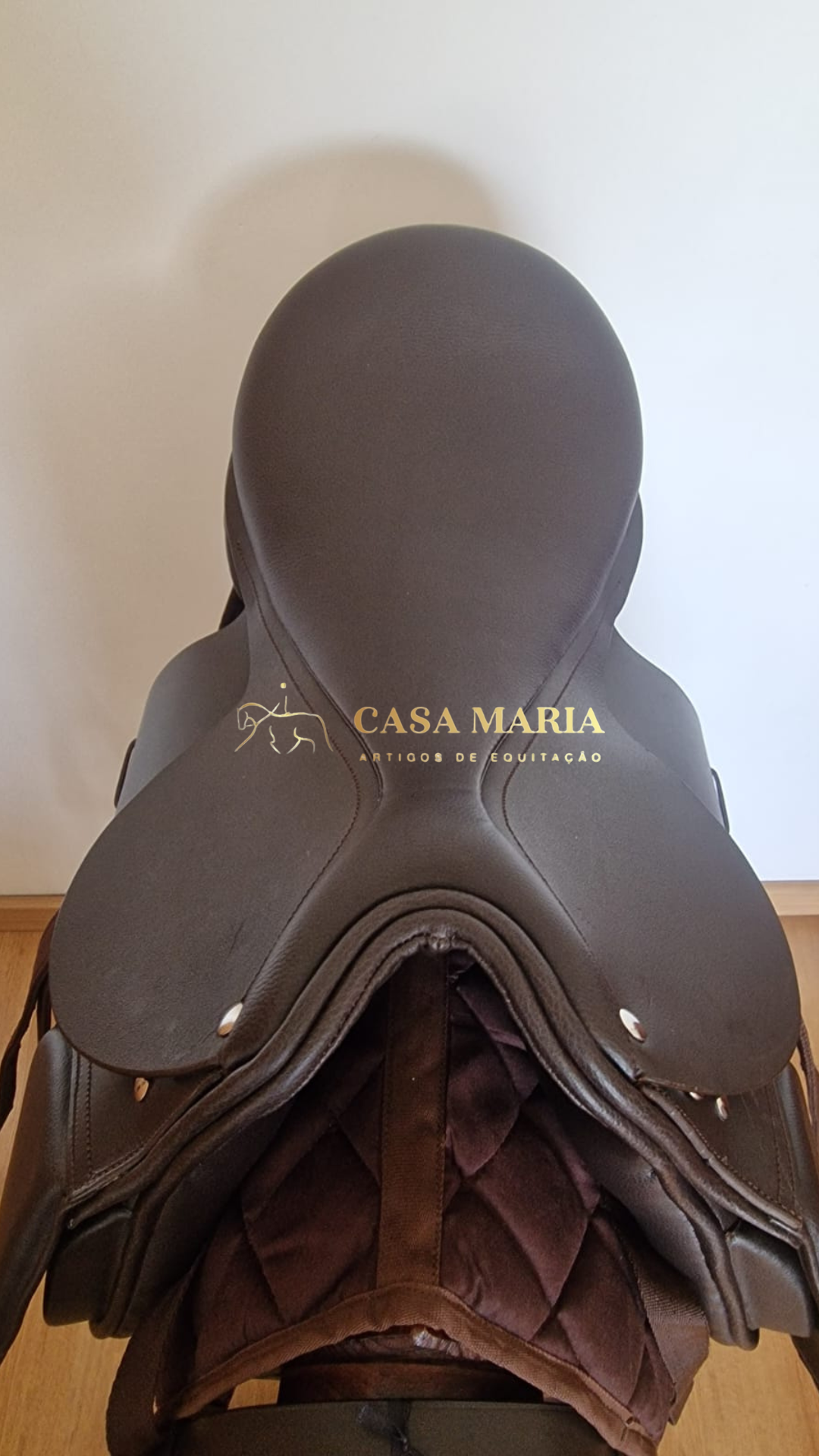 Sela de equitação castanha escura sobre acolchoamento matelado castanho