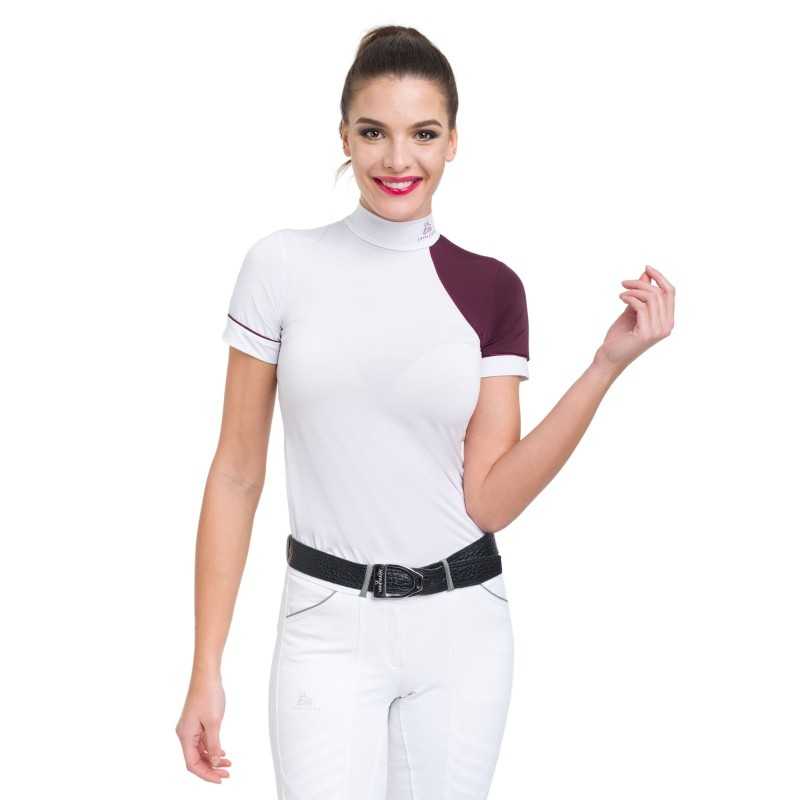 Mulher com camisa branca e detalhe bordô no ombro direito, jeans brancos e cinto preto