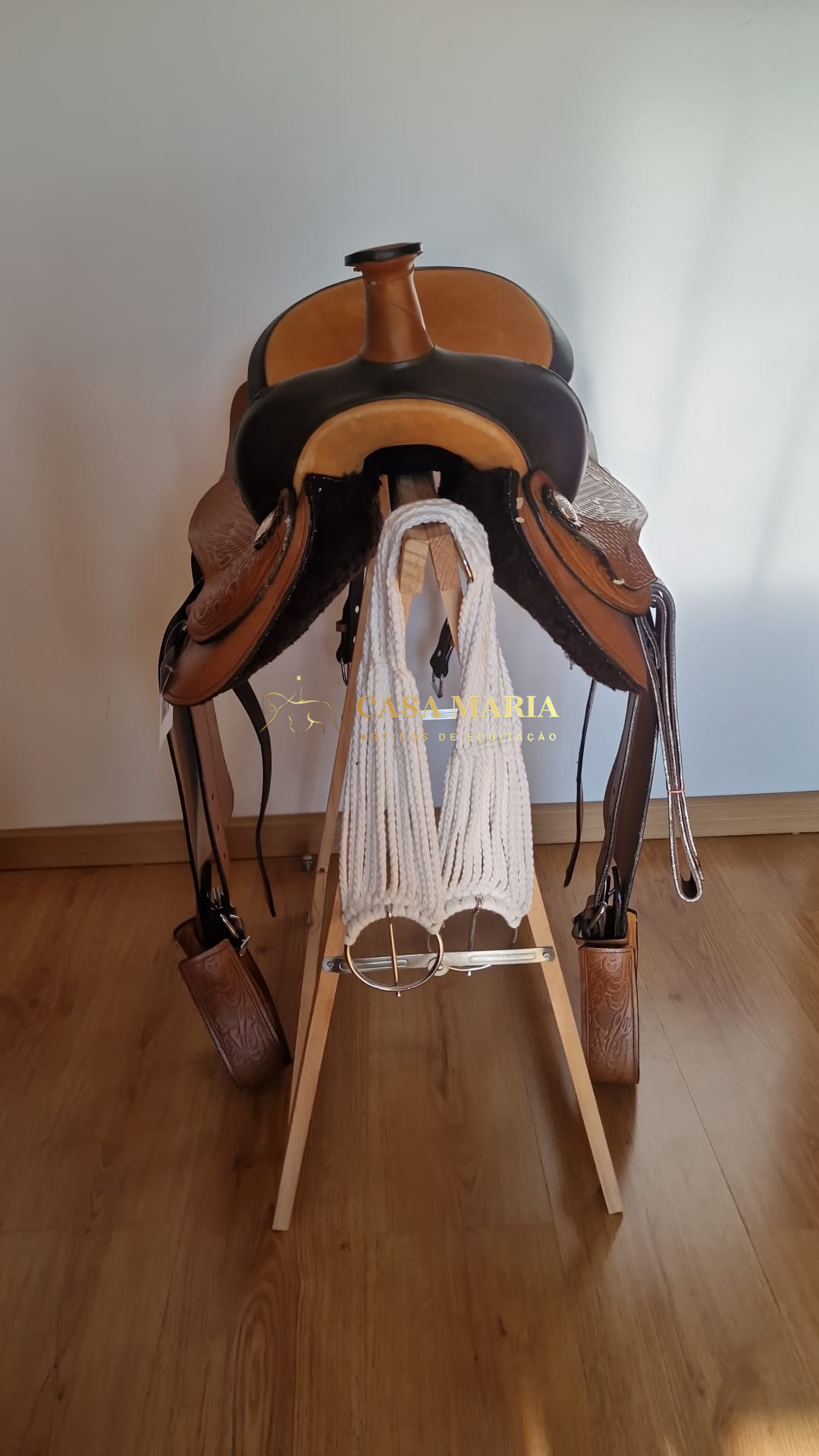 Sela de equitação em couro castanho claro e escuro num suporte de madeira