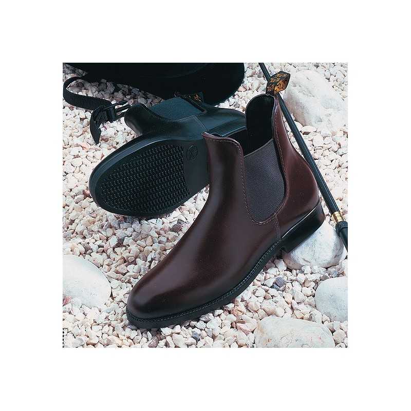 Botas Chelsea de pele castanha com sola preta sobre cascalho