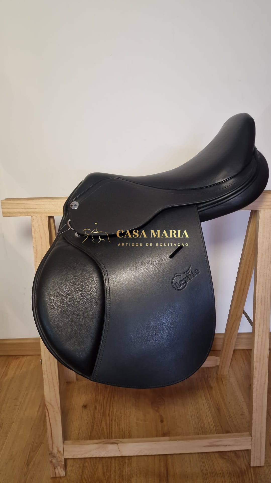 Sela de equitação preta em suporte de madeira com logotipo Casa Maria e marca Prestige