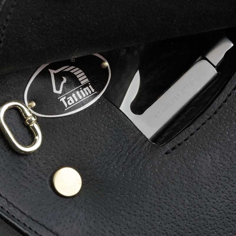 Chaveiro metálico com fecho mosquetão sobre superfície preta de couro e lâmina metálica com texto