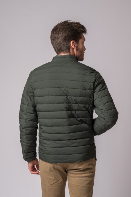 Homem de costas com casaco acolchoado verde escuro e calças castanhas