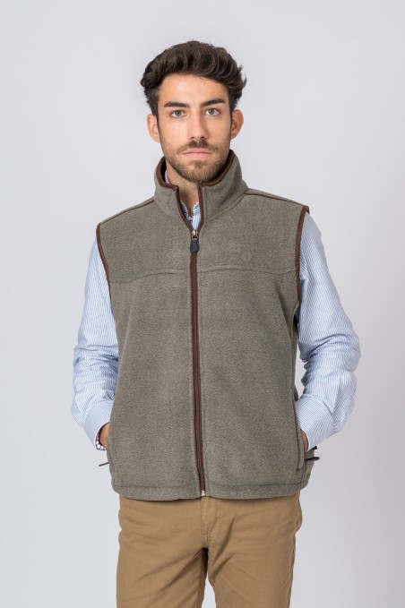 Colete masculino cinza de fleece com fecho castanho sobre camisa azul listrada e calças bege