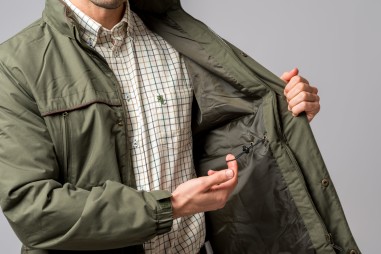 Homem a usar casaco verde oliva acolchoado por dentro e camisa quadriculada