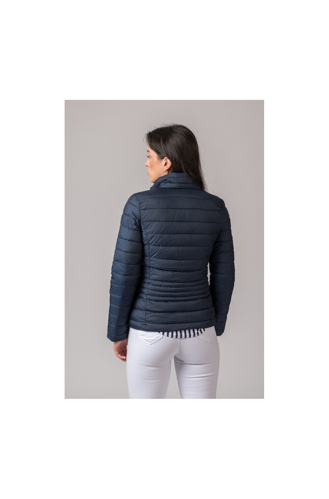 Casaco acolchoado azul escuro visto por trás usado com calças brancas