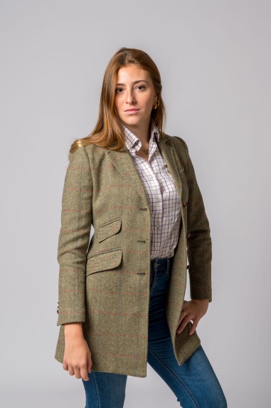 Mulher vestindo casaco comprido verde xadrez, camisa de quadrados e calças jeans azuis