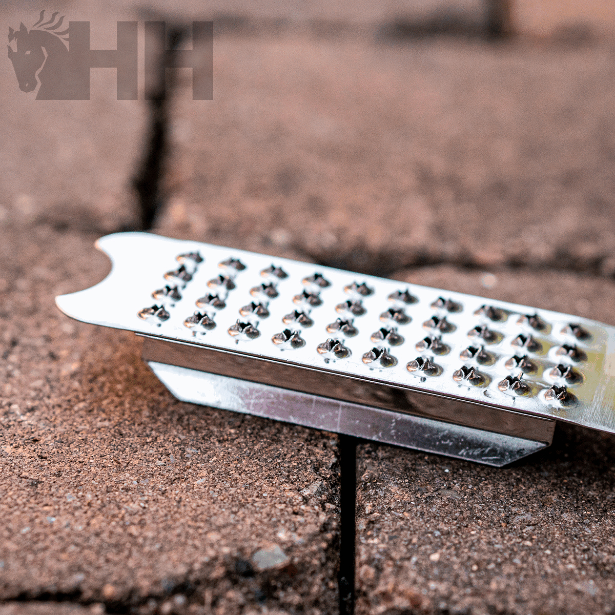 Ralador metálico prateado sobre chão de tijolos castanhos