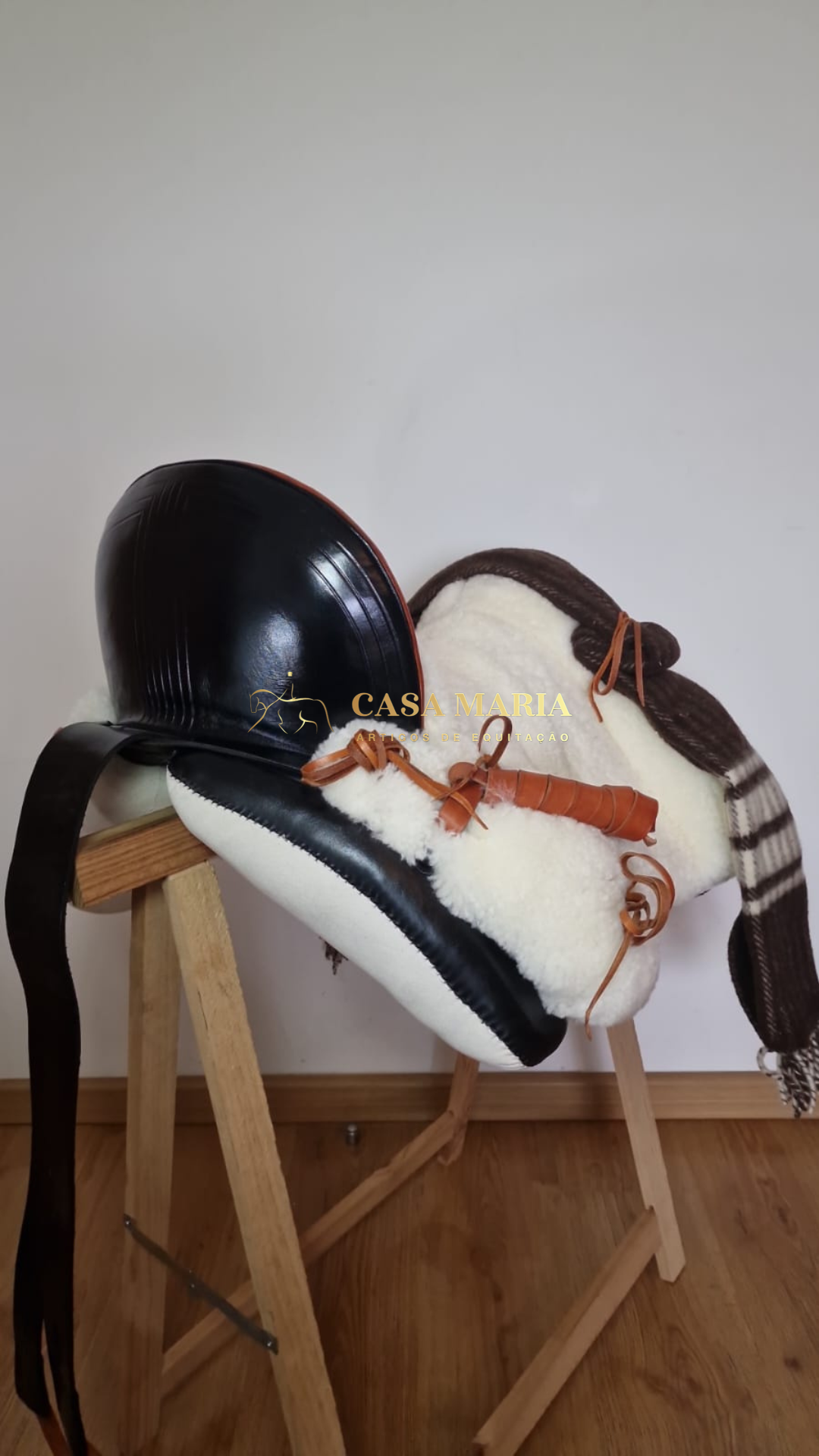 Sela de cavalo com pelúcia branca e couro castanho e preto sobre suporte de madeira
