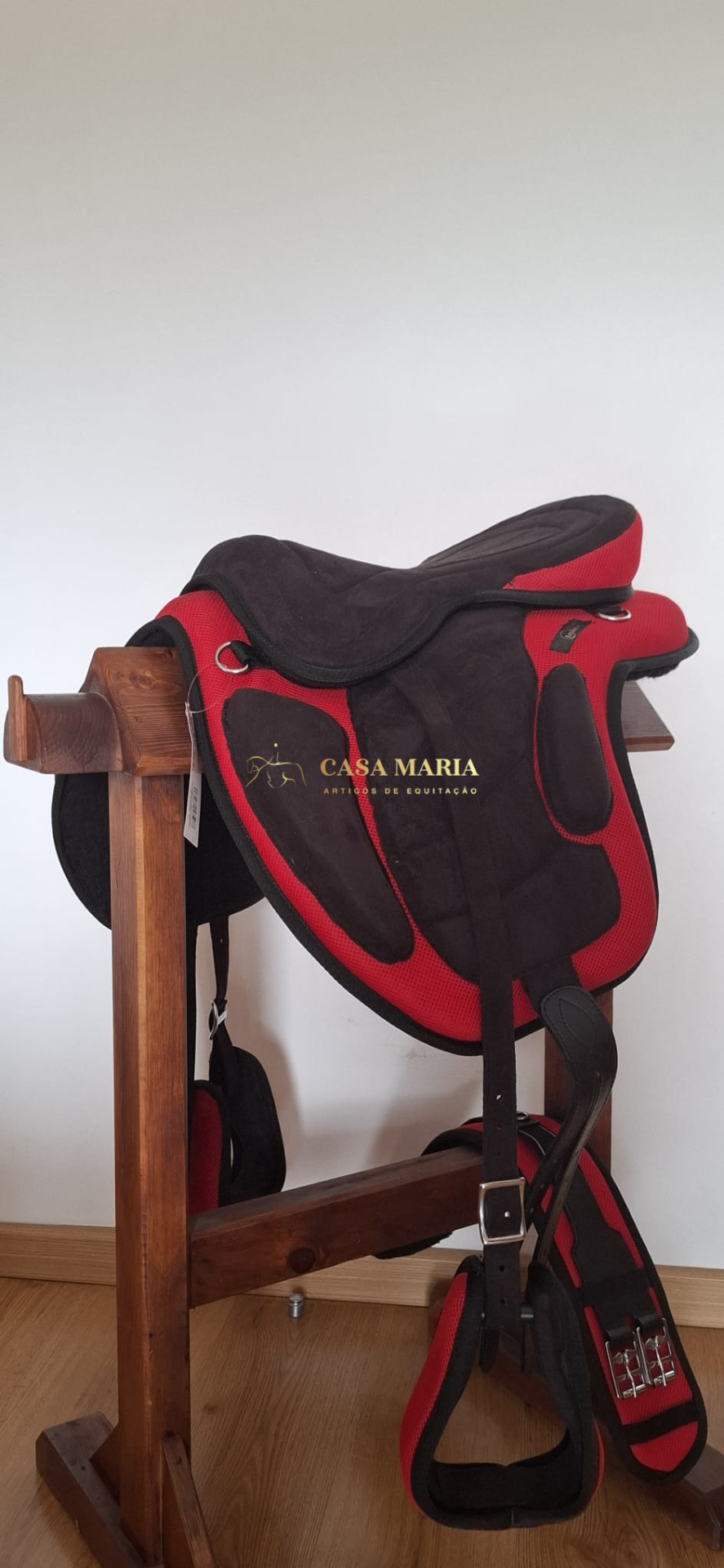 Sela de equitação preta e vermelha em suporte de madeira