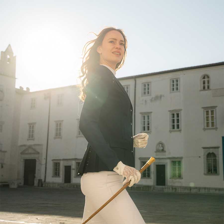 Mulher com roupa formal e bastão de madeira ao ar livre em frente a edifício histórico