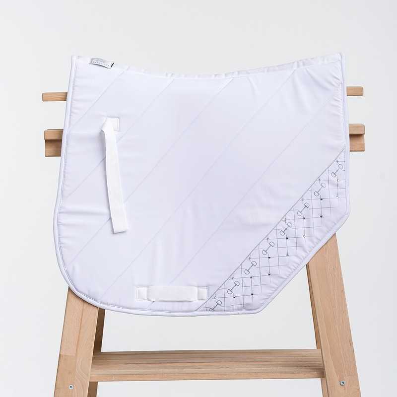 Sela branca para cavalo com padrão geométrico e alças pendurada em estrutura de madeira